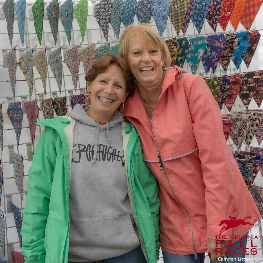 two smiling women with colorful flags at vendor booth
