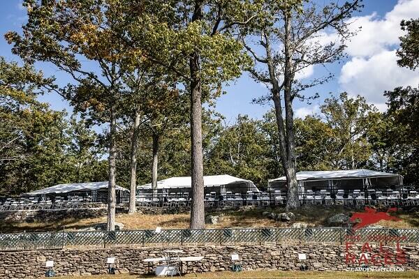 tents and chairs overlooking race course above stone wall fence