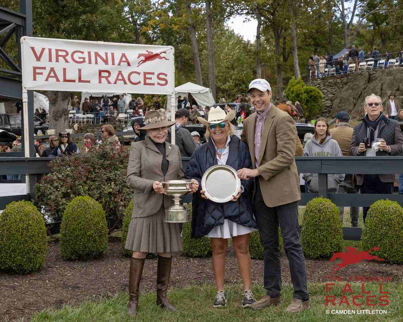 smiling people holding trophies in front of spectators